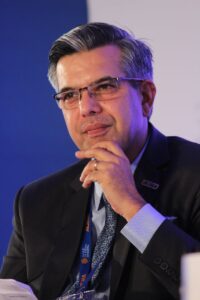 Portrait d'un homme d'affaires réfléchi en costume, portant des lunettes, capturé dans un cadre d'entreprise intérieur.